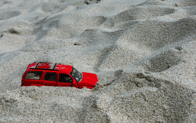 Toy car stuck in sandy beach during sunny day