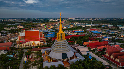 Naklejka premium Aerial view of The moon is situated on top of the golden umbrella of the golden pagoda Wat Ketmadi Sriwararam.. a magnificent golden pagoda surrounded by temple buildings...