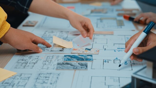 Hands engage in collaborative brainstorming over architectural plans and sketches, showcasing teamwork and creativity in a dynamic workspace filled with notes and drawings. SACTR