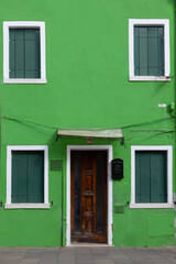 Bright green house with closed shutters in Burano Italy