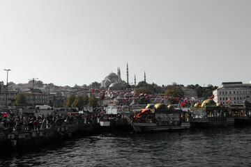 Bathed in bright daylight, a dynamic scene features the magnificent Süleymaniye Mosque (Süleymaniye Camii) with its elegant domes and slender minarets rising above the cityscape.