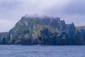 Fog and mist envelop the top of a high ridge cliff face on Cape Horn, Chile.