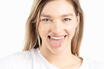 Beauty, wellness, fashion, make-up and style concept. Beautiful happy blonde woman with sticking out her tongue studio portrait against white background