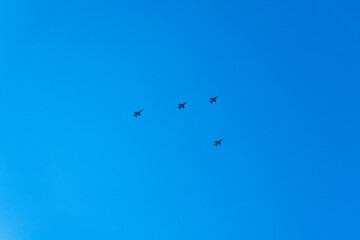Four fighter jets flying in tight formation across a clear blue sky during daytime.