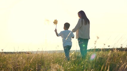 serene setting park sunset mother lovingly clasps son hand. joyful family, strolling together...