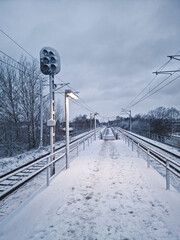 Snow covered S-tog rail lines and an empty platform in Denmark, depicting a serene winter scene.