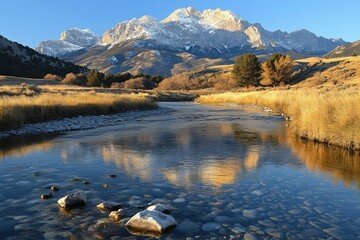 Fototapeta premium Majestic snow-capped mountains reflected in a calm river, serene autumnal landscape.