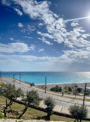 Seaside promenade with turquoise sea, coastal road and dramatic blue sky on a sunny day © Kateryna