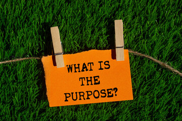 What is the purpose message written on ripped torn orange paper piece on green grass background....