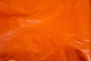 Crumpled orange plastic bag closeup texture background