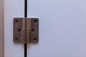 Detailed closeup of a Stainless Steel Door Hinge mounted on a Modern White Cabinet design