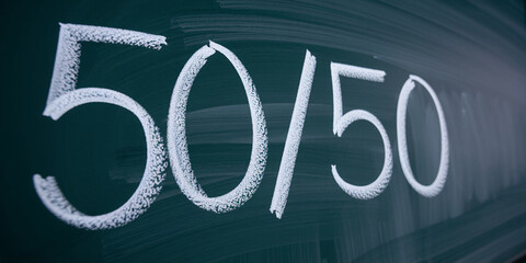 Chalkboard with white chalk inscription 50/50, representing choice, balance, or decision-making, ideal for educational or business contexts