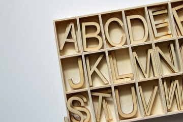 Wooden English alphabet letters arranged in cells, alphabet letters in a box, school