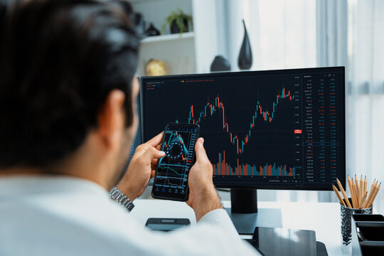 Trader businessman searching on smartphone, analyzing in dynamic stock exchange investment screen on pc with invest highest profitable financial technology market at modern home office. Surmise.