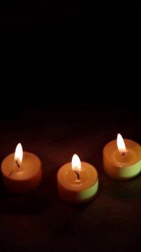 Una toma de cerca de tres velas de color  amarillo en la oscuridad