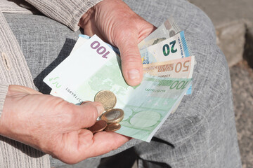 Euro banknotes and coins in the hands of an elderly woman.