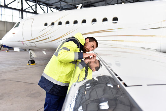 Aircraft mechanic inspects and checks the technology of a jet in a hangar at the airport