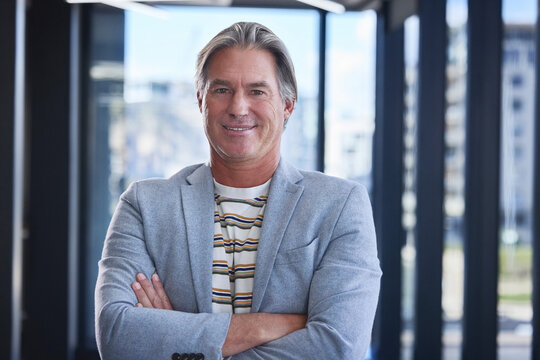 Portrait, business and man with arms crossed, modern office and confidence with career ambition. Face, mature person and entrepreneur with entertainment agency, public relations officer and smile
