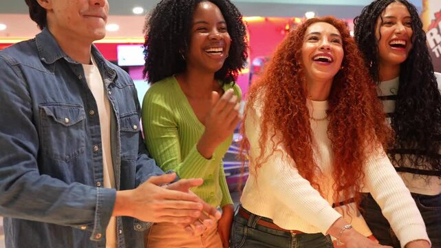 Young adults enjoying arcade games, cheering and having fun together in a vibrant entertainment venue, captured in slow motion