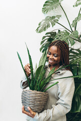 A woman lovingly nurturing her indoor plant in a beautifully arranged natural greenery setting