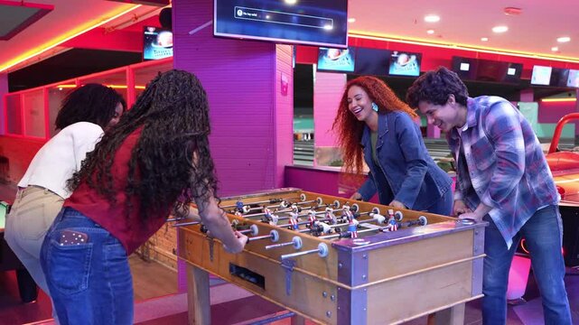 Young adults enjoying a friendly game of foosball in slow motion, adding excitement to their bowling alley outing