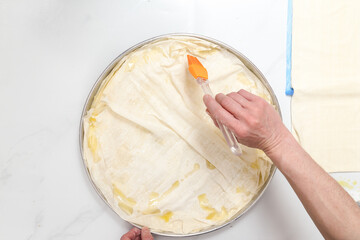 woman in kitchen adding olive oil to spinach pie