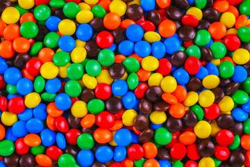 Colorful candy-coated chocolates in a vibrant, playful pile. Bright red, blue, yellow, green, and orange sweets create a cheerful, festive background perfect for parties, designs, and advertisements.