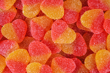 Colorful sugar-coated heart-shaped candies in vibrant red and yellow tones. Sweet, chewy texture creating a festive and romantic background perfect for Valentines Day designs and celebrations.