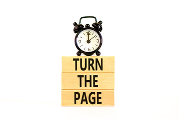 Turn the page symbol. Concept words Turn the page on beautiful wooden block. Black alarm clock....