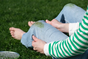 A unrecognizable person showing dirty grass stains kneeled jeans and sitting on the grass. top view.