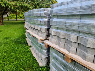 Stacks of grey interlocking paving stones on pallets, ready for landscaping project or home renovation