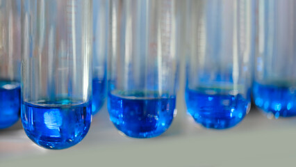 A row of blue test tubes are lined up on a table. Analytics medicine pharmaceuticals microbiology concept background