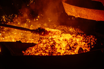 Removing slag from surface of hot iron in melting furnace, close up