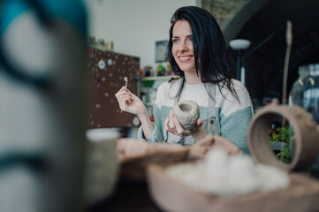 Ceramist smiling and creating pottery in workshop