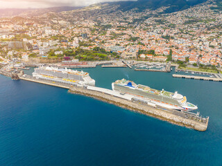Fototapeta premium Cruise ships anchor in vibrant harbor, surrounded by stunning coastal city and clear blue waters during a sunlit afternoon