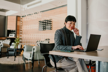 Asian businesswoman working on laptop in modern office