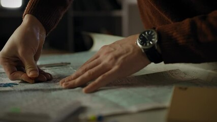A person focuses on a detailed map, placing markers while planning a route. The atmosphere suggests careful consideration and exploration happening in a cozy indoor environment