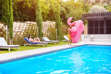 Water, holiday and couple with inflatable in swimming pool for summer vacation, weekend break or...