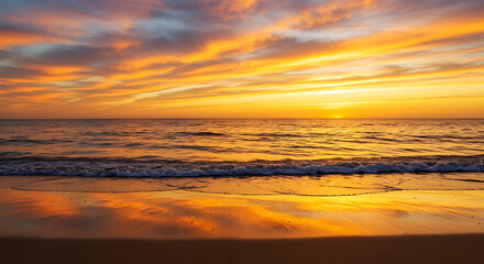 Fototapeta premium Vibrant golden serene ocean sunset with warm orange and yellow clouds reflecting on the calm water and wet beach, concept for travel promotion, relaxation content and nature backgrounds