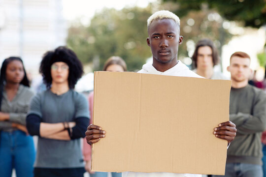 African american guy with empty placard for text and taglines leading group of young multiracial protestors. International group of demonstrators fighting against racism, standing on the street