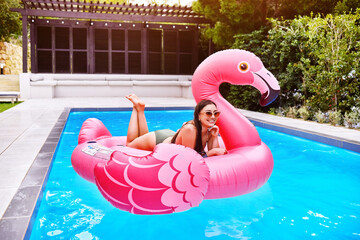Woman, relax and flamingo in swimming pool for holiday, summer and sunshine for vacation. Female person, sleeping and inflatable bird in water for travel, calm or zen and float for weekend in Miami © Dean2000/peopleimages.com