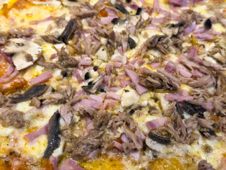 Close-up of artisan pizza with ham, tuna and mushrooms