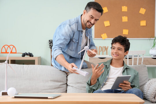 Father with wind turbine model and his son using tablet computer at home
