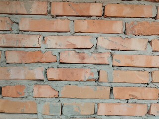 Fototapeta premium Rustic brick wall with varying shades of orange and grey mortar. Offers a textured and industrial feel, suitable for backgrounds and architectural designs