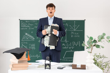 Handcuffed male teacher with briefcase and bribe in classroom. Corruption concept