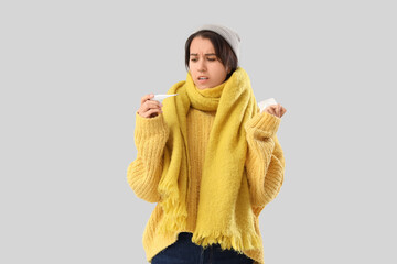 Sick young woman with thermometer on grey background