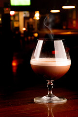 glass of chocolate cognac cocktail with smoke coffee and cinnamon with blurred pub background