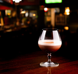 glass of chocolate cognac cocktail with coffee and cinnamon with blurred pub background
