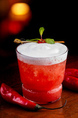 spicy red cocktail with peppers and spicy ginger foam with blurred background
