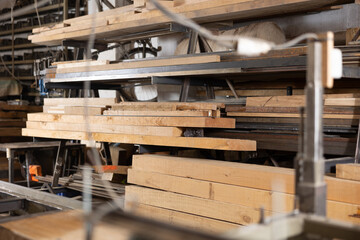 Cutting machine for wood on background of stacks of wooden planks in workshop
